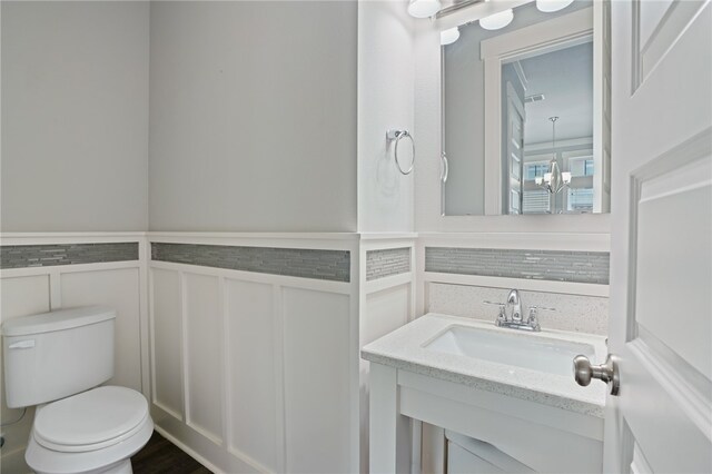 bathroom featuring toilet, vanity, and a chandelier