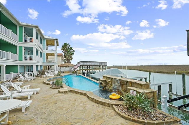 view of swimming pool featuring a patio, a water view, and a boat dock