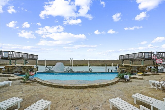 view of swimming pool with a water view and a patio area