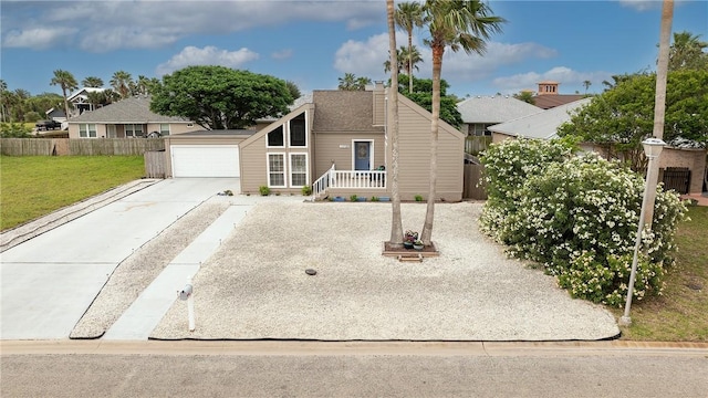 view of front of property featuring concrete driveway, a front lawn, an attached garage, and fence