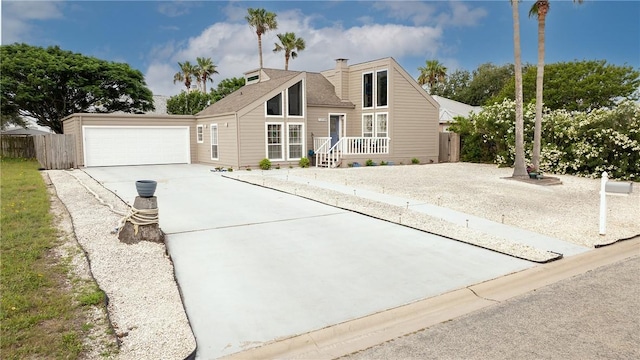 mid-century modern home with fence, a chimney, and concrete driveway