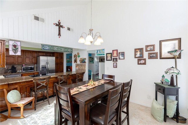 dining space featuring a toaster, a high ceiling, visible vents, and a chandelier