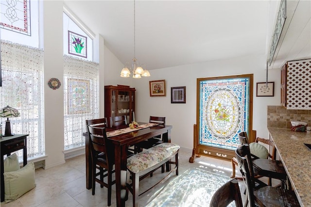 dining room with a wealth of natural light, a chandelier, light tile patterned floors, and vaulted ceiling