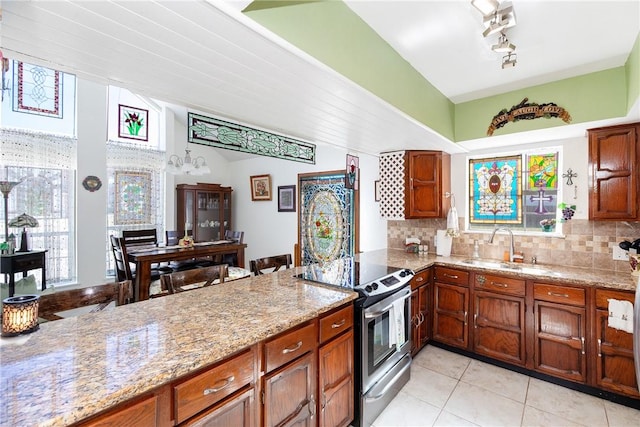 kitchen featuring light stone counters, decorative backsplash, brown cabinets, a sink, and stainless steel range with electric stovetop