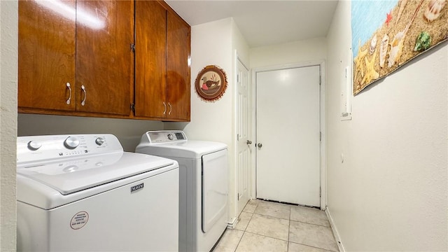 laundry room featuring separate washer and dryer, baseboards, cabinet space, and light tile patterned flooring
