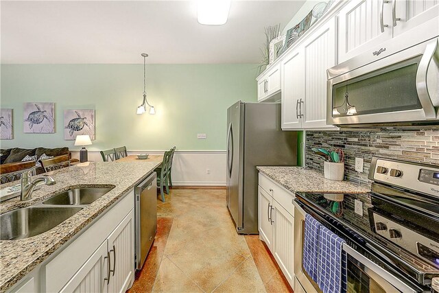 kitchen with decorative backsplash, pendant lighting, a sink, white cabinets, and stainless steel appliances