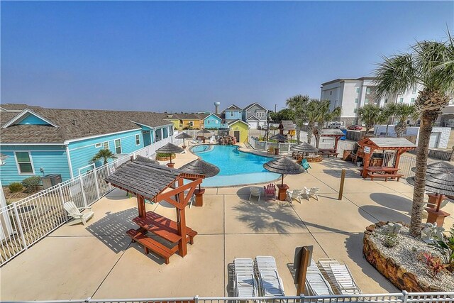 community pool with fence, a patio area, and a residential view