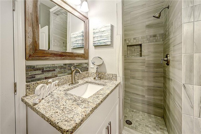 bathroom with tiled shower and vanity