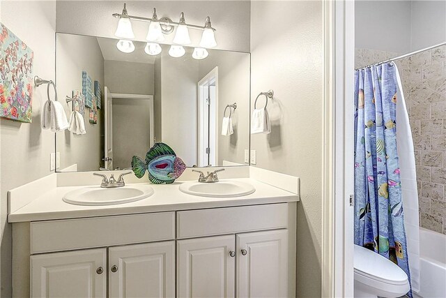 bathroom with double vanity, toilet, a sink, and shower / bath combo with shower curtain