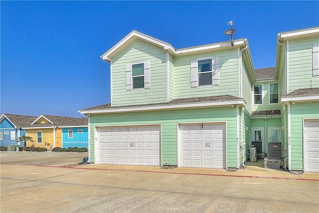 view of front of property with concrete driveway, an attached garage, and central AC