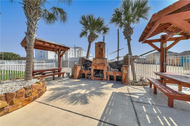 view of patio with fence and an outdoor stone fireplace