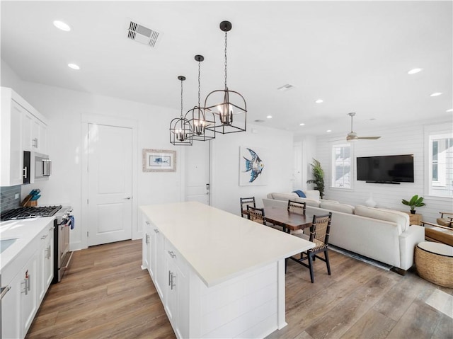 kitchen with visible vents, light wood-style flooring, light countertops, white cabinets, and appliances with stainless steel finishes