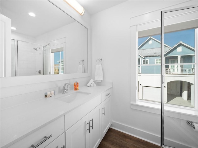 full bath featuring a stall shower, wood finished floors, recessed lighting, baseboards, and vanity