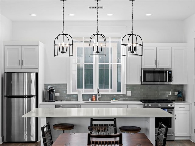 kitchen with a kitchen breakfast bar, a notable chandelier, appliances with stainless steel finishes, and a sink