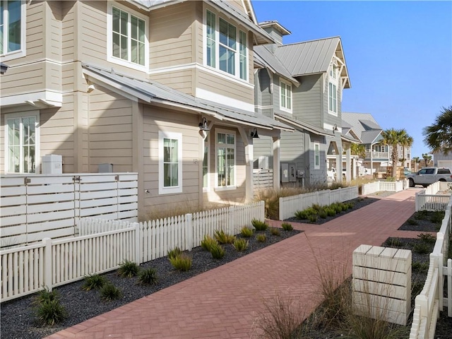 view of side of home featuring metal roof, a residential view, and a fenced front yard