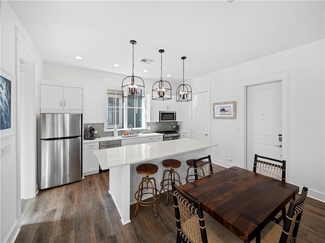 kitchen with visible vents, a sink, backsplash, appliances with stainless steel finishes, and dark wood-style flooring