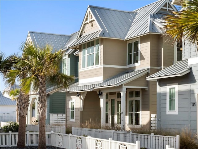 view of front of home featuring metal roof, a fenced front yard, and a standing seam roof