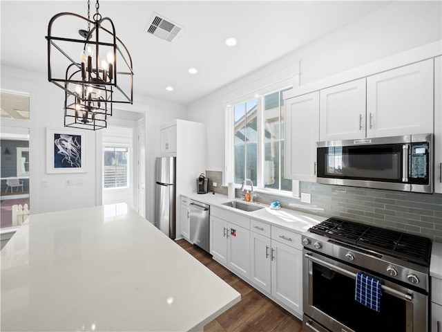 kitchen with visible vents, dark wood finished floors, a sink, stainless steel appliances, and a chandelier