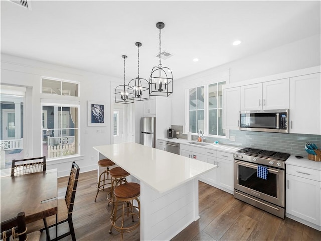 kitchen featuring visible vents, backsplash, a sink, appliances with stainless steel finishes, and dark wood-style flooring