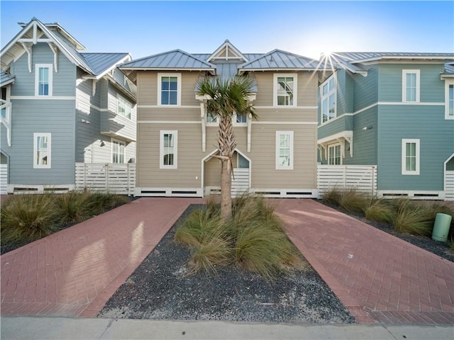 view of front facade with metal roof, a standing seam roof, and fence