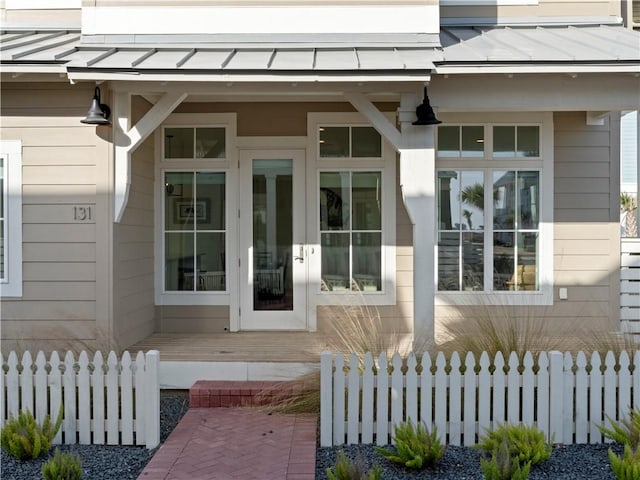 doorway to property featuring a standing seam roof, fence, and metal roof