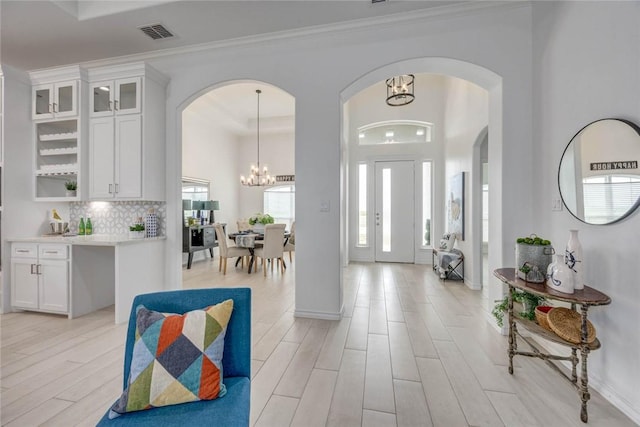 104 Emerald St, Portland, TX 78374 - foyer entrance featuring a chandelier, arched walkways, light wood finished floors, and ornamental molding