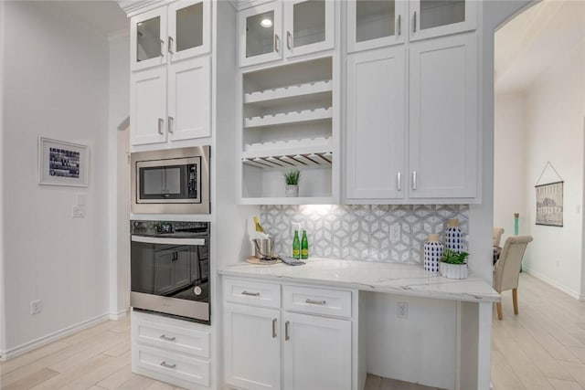 104 Emerald St, Portland, TX 78374 - kitchen featuring stainless steel appliances, backsplash, light stone counters, light wood-type flooring, and white cabinetry