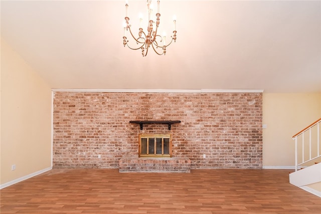 unfurnished living room featuring hardwood / wood-style floors, a notable chandelier, a brick fireplace, and brick wall