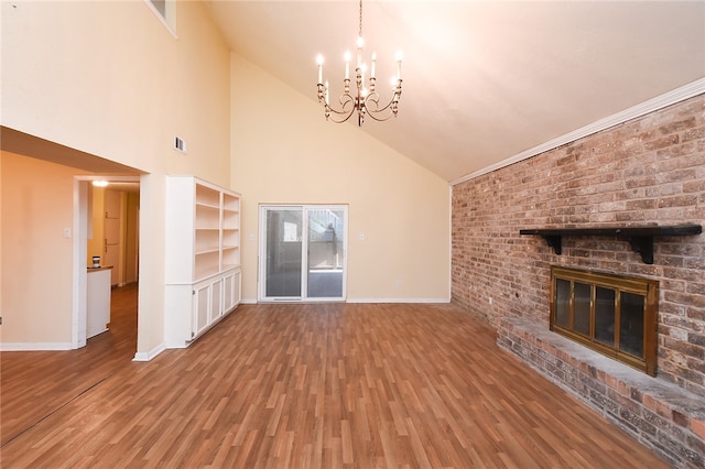 unfurnished living room featuring a brick fireplace, hardwood / wood-style floors, high vaulted ceiling, and an inviting chandelier