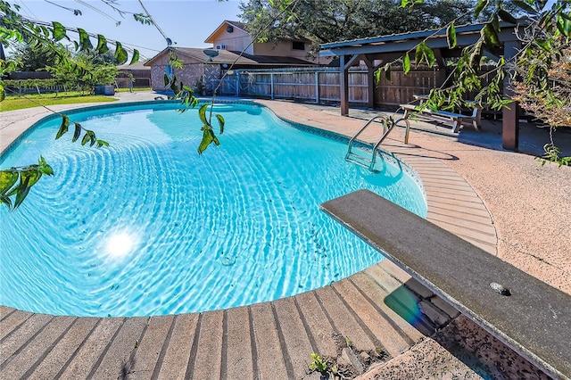 view of swimming pool featuring a patio and a diving board