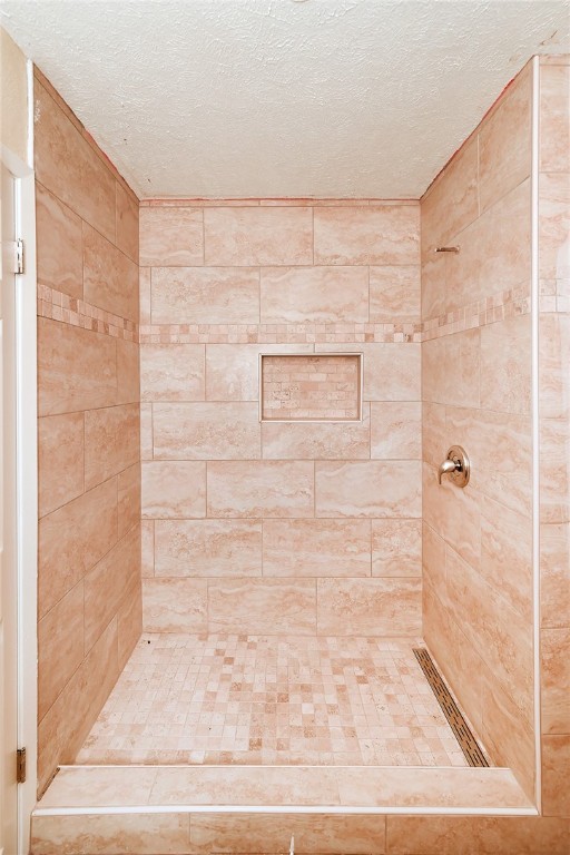 bathroom featuring a textured ceiling and tiled shower