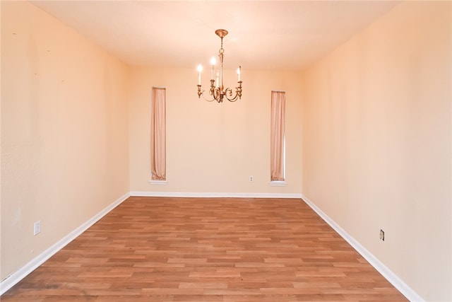 unfurnished room featuring hardwood / wood-style flooring and a notable chandelier