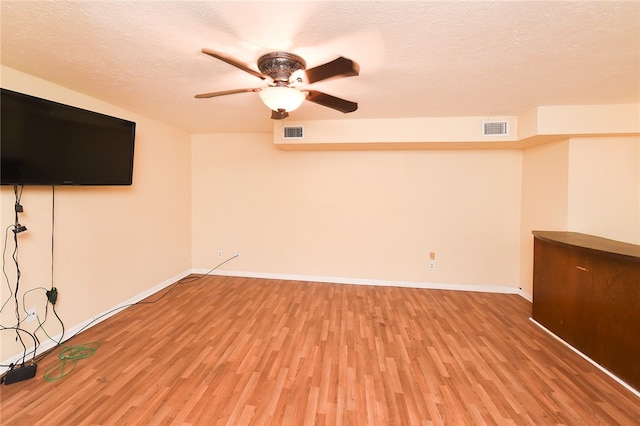 spare room with a textured ceiling, ceiling fan, and light hardwood / wood-style flooring