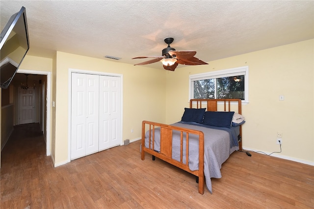 bedroom with ceiling fan, a textured ceiling, a closet, and wood-type flooring