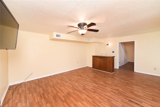 unfurnished living room with a textured ceiling, hardwood / wood-style flooring, and ceiling fan