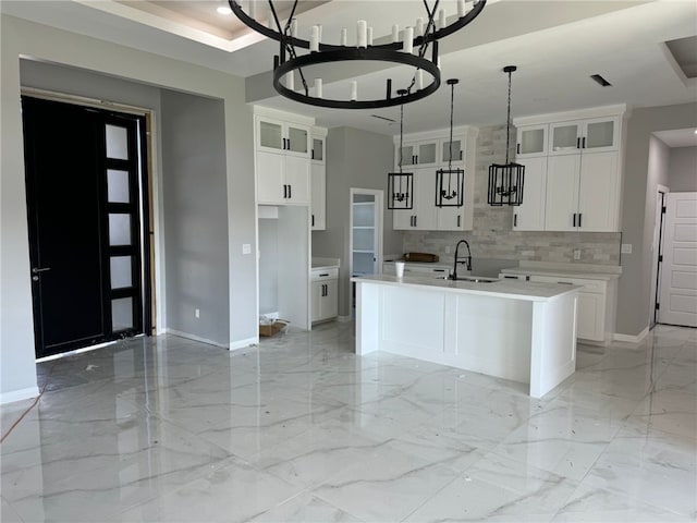 kitchen with sink, a chandelier, decorative light fixtures, a kitchen island with sink, and white cabinets