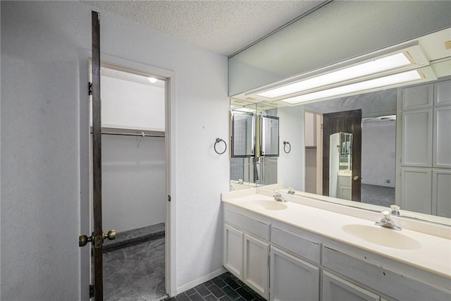 743 Retama Ave, Taft, TX 78390 - bathroom featuring double vanity, a textured ceiling, tile patterned flooring, and baseboards