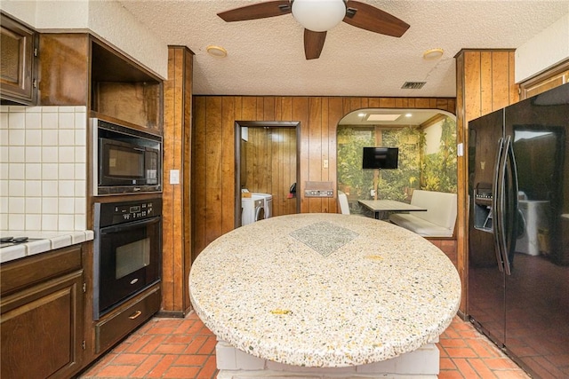 743 Retama Ave, Taft, TX 78390 - kitchen with black appliances, washing machine and clothes dryer, a ceiling fan, a kitchen island, and tasteful backsplash
