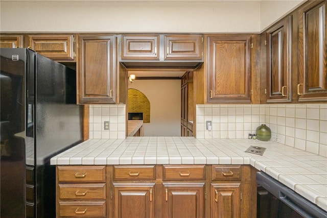 743 Retama Ave, Taft, TX 78390 - kitchen featuring freestanding refrigerator, dishwasher, tasteful backsplash, light countertops, and brown cabinetry