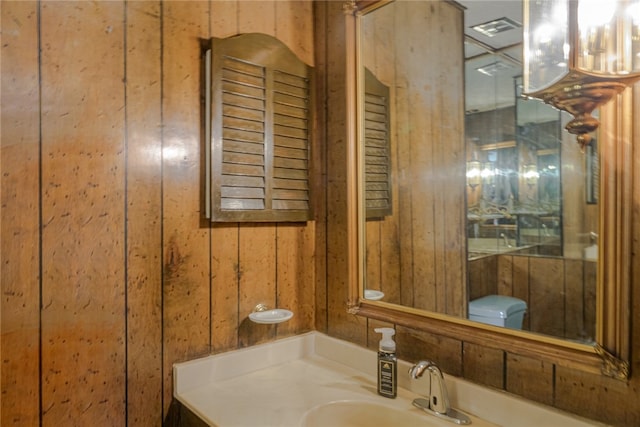 bathroom with vanity, wooden walls, and toilet