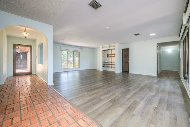 unfurnished living room featuring wood-type flooring and a textured ceiling