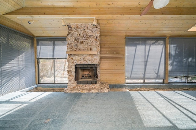 unfurnished living room featuring a stone fireplace, carpet flooring, vaulted ceiling, and wood ceiling