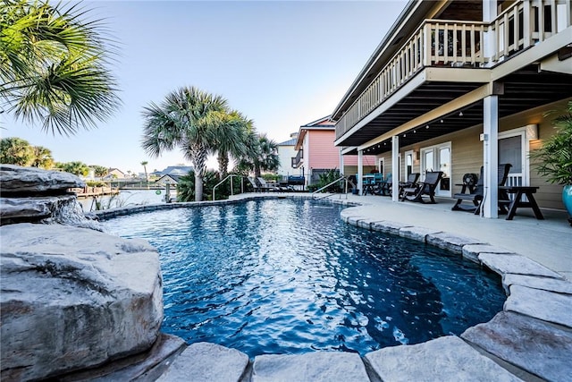 view of pool featuring a water view, pool water feature, and a patio area