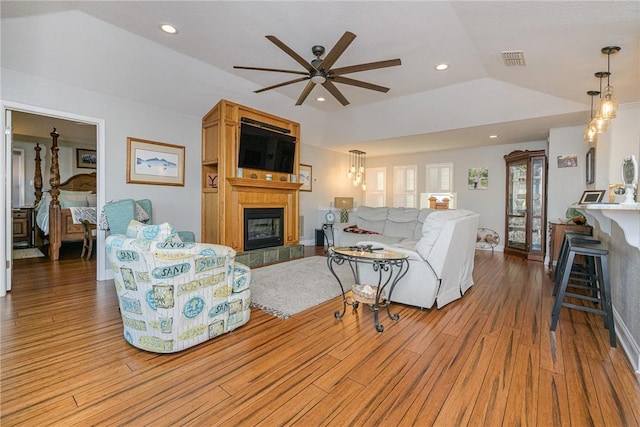 living room featuring a tiled fireplace, ceiling fan, vaulted ceiling, and light wood-type flooring