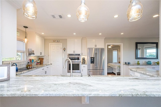 kitchen with white cabinetry, hanging light fixtures, tasteful backsplash, and appliances with stainless steel finishes