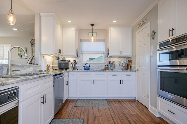 kitchen featuring stainless steel appliances, decorative light fixtures, sink, and white cabinets