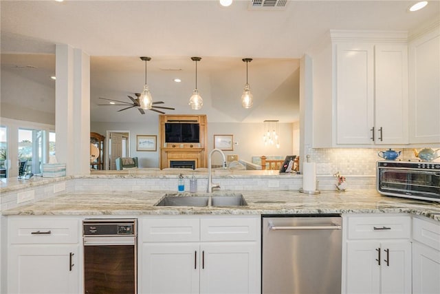 kitchen featuring sink, hanging light fixtures, light stone countertops, white cabinets, and stainless steel dishwasher