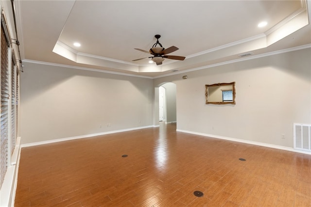 spare room featuring hardwood / wood-style flooring, ceiling fan, crown molding, and a tray ceiling