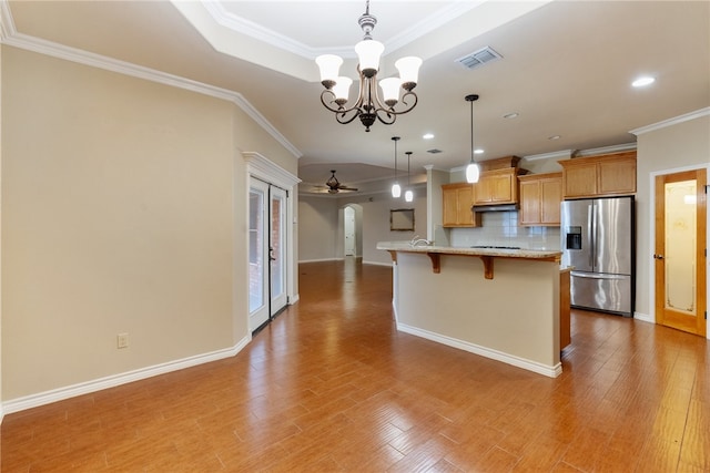 kitchen with hardwood / wood-style floors, a breakfast bar area, tasteful backsplash, stainless steel fridge with ice dispenser, and decorative light fixtures