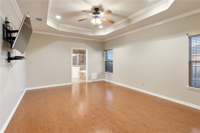 unfurnished room featuring ceiling fan, a raised ceiling, light hardwood / wood-style floors, and crown molding